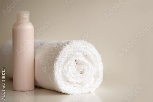 Clean white towel rolled blanket textile and Close-up of a jar of cream for the skin on white table. Horizontal shoot.
