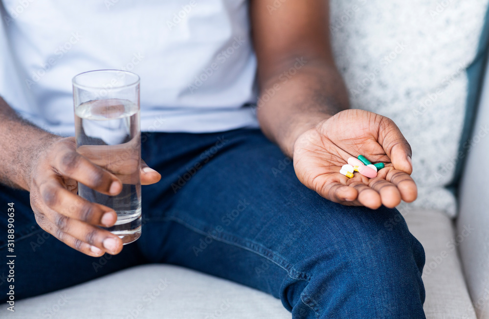 Pile of pills with water glass in hands of african man Pile of pills with water glass in hands of african man