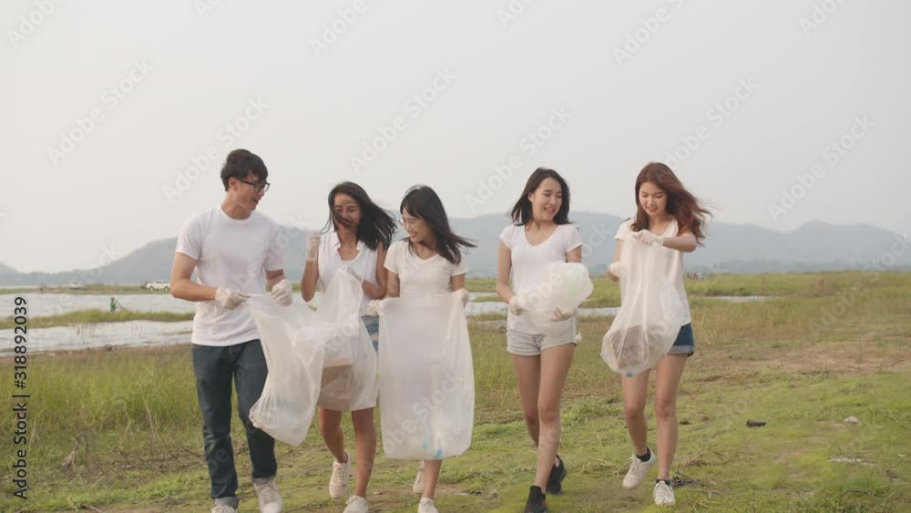 Group of young multiethnic activists collecting plastic waste and walking on beach. Asia volunteers help to keep nature clean up garbage. Concept about environmental conservation pollution problems. Group of young multiethnic activists collecting plastic waste and walking on beach. Asia volunteers help to keep nature clean up garbage. Concept about environmental conservation pollution problems.