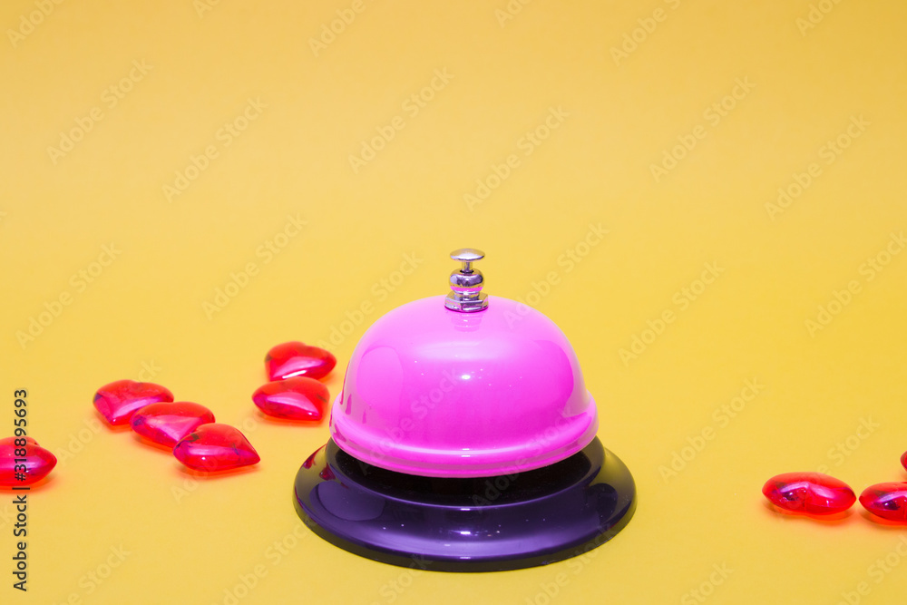 restaurant service pink bell on a yellow background, small red hearts lie next to each other, copy space restaurant service pink bell on a yellow background, small red hearts lie next to each other, copy space