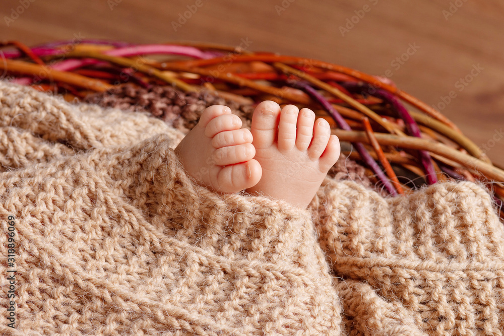 Tiny foot of newborn baby. Soft newborn baby feet against a beige