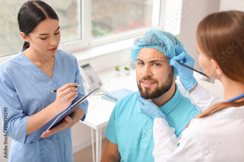 Plastic surgeon applying ma...