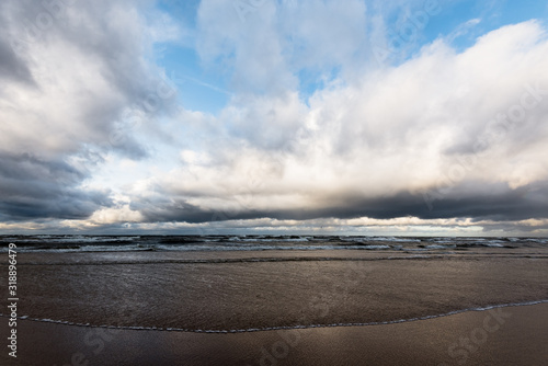 Storm clouds above the sea. Waves and water splashes. Warm evening sunlight. Baltic sea, Garciems, Latvia photo