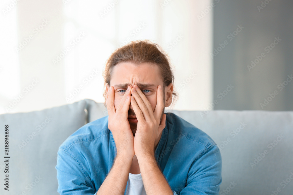 Depressed man sitting on sofa at home Depressed man sitting on sofa at home