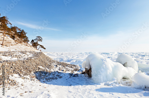 Icy and snowy shore of Baikal Lake on a frosty winter day. Ice hummocks cover the surface of the lake. Beautiful winter landscape. Natural background © Katvic