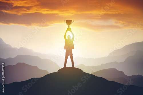 Silhouette of a man holding a trophy at sunset photo