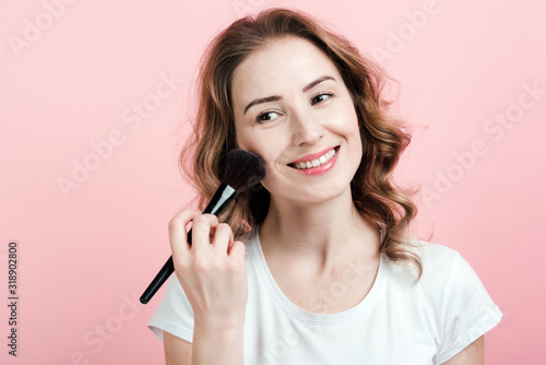 Beautiful woman .applies blush with a brush. Make up