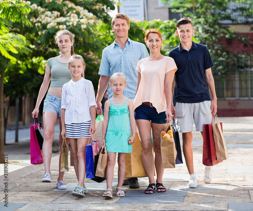 Man and woman with four kids walking and holding shopping bags