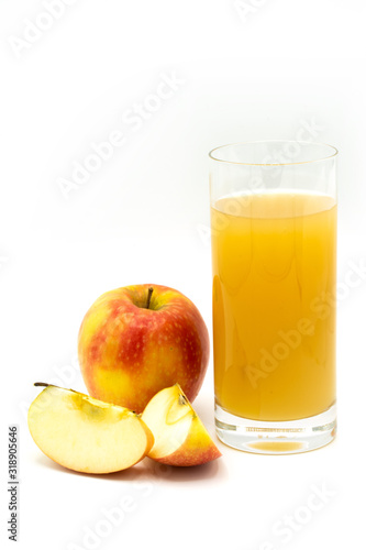 apple juice - sliced yellow, ​red apples and a glass of naturally cloudy apple juice in front of white background