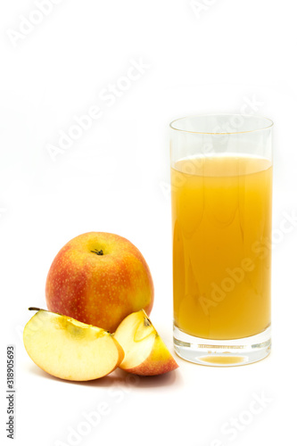 naturally cloudy apple juice - sliced yellow, ​red apples with a glass of naturally cloudy apple juice in front of white background