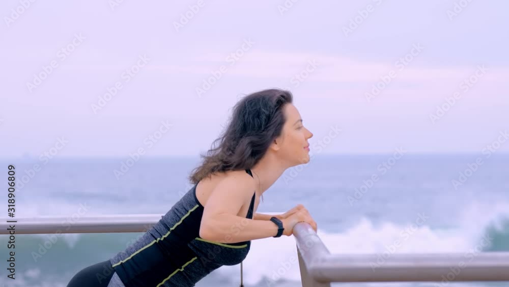 Active woman in sport clothes on the seashore doing sport exercises Active woman in sport clothes on the seashore doing sport exercises