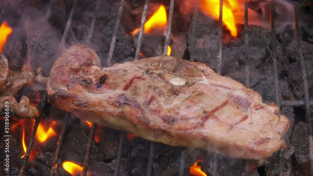 Pieces of pork meat steak falling on the grill with flames bursts Pieces of pork meat steak falling on the grill with flames bursts