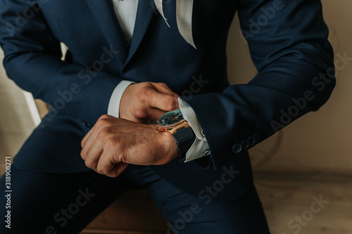 businessman in black costume wind clock (wristwatch) on hand