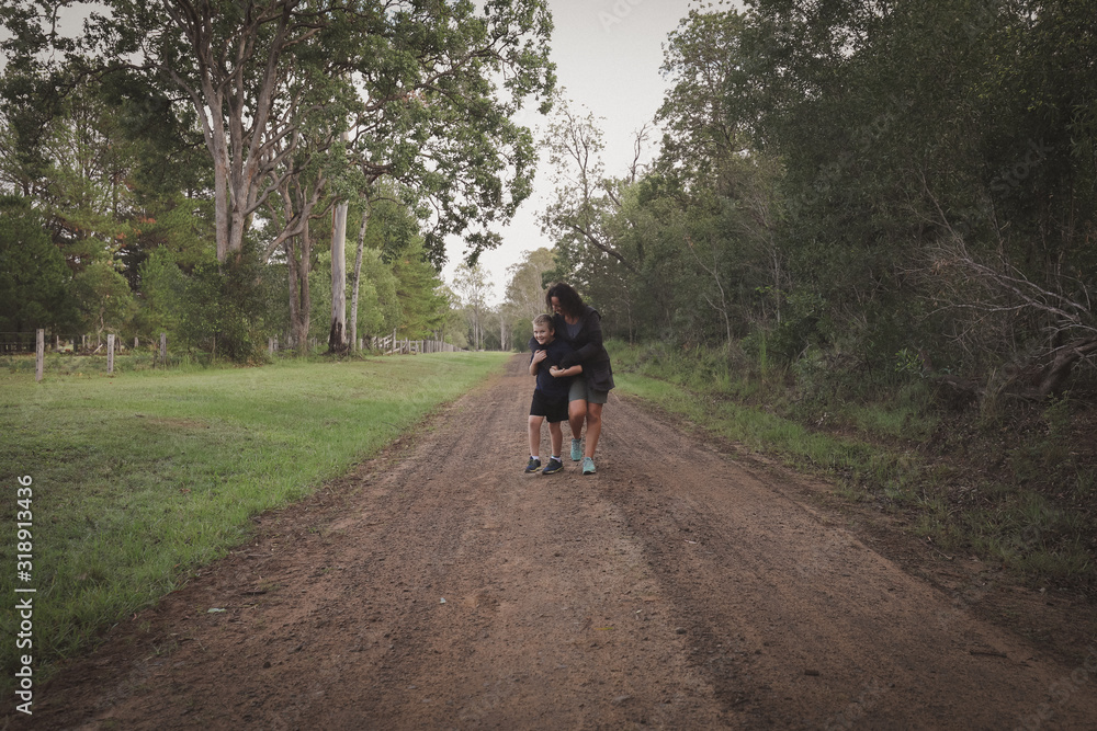 Fototapeta premium Mother and son walking together down country lane