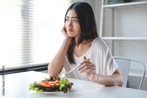 The girl has a boring expression when she eats vegetables. She wants to eat delicious food. Diet  Clean food  Healthy food concept.