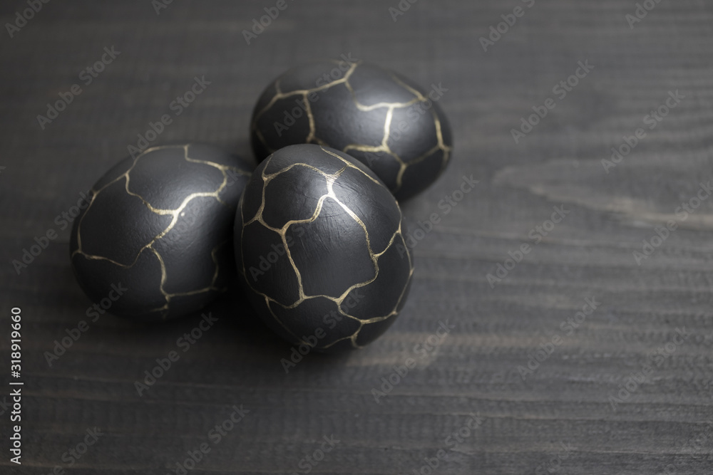 Fototapeta premium Painted eggs in black color with golden patterns on a wooden background. Preparing for the Easter holiday.