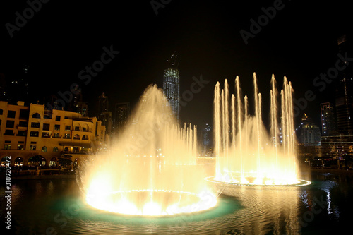 Water & Light show in the downtown city at night with all the skyscrappers illluminated and reflecting in the lake, Dubai, United Arab Emirates.