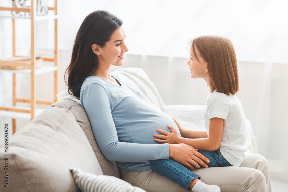 Expecting mother having conversation with her little daughter