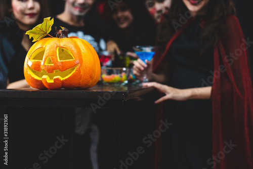 Closeup image of a pumpkin. A group of people were celebrating the Halloween behind.
