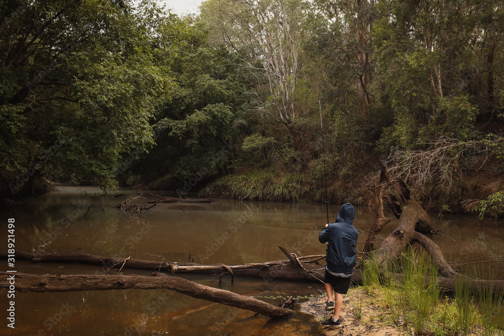 Young boy fresh water fishing in low river during times of drought Young boy fresh water fishing in low river during times of drought