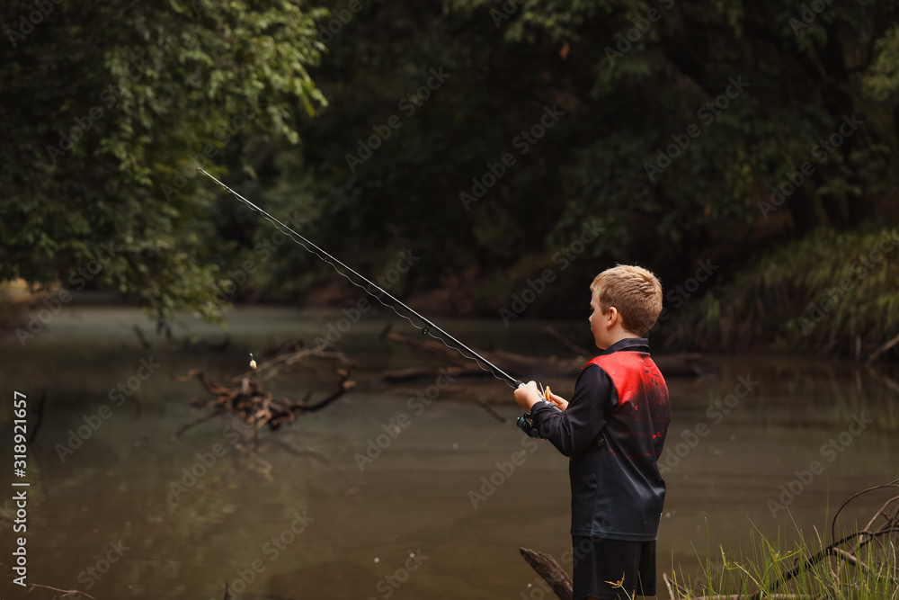Young boy fresh water fishing in isolated river in New South Wales, Australia Young boy fresh water fishing in isolated river in New South Wales, Australia