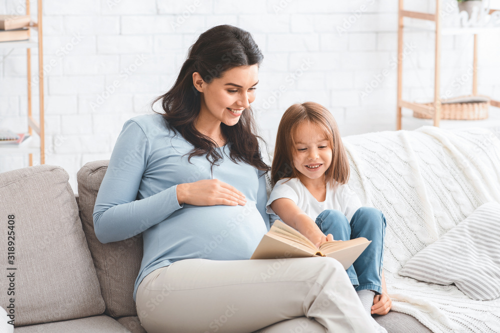 Adorable little girl and her expecting mother reading book Adorable little girl and her expecting mother reading book