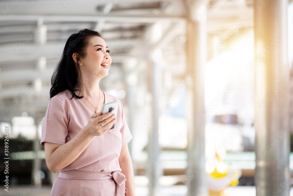 Elder woman traveler walking with holding smartphone in cityscape background Elder woman traveler walking with holding smartphone in cityscape background