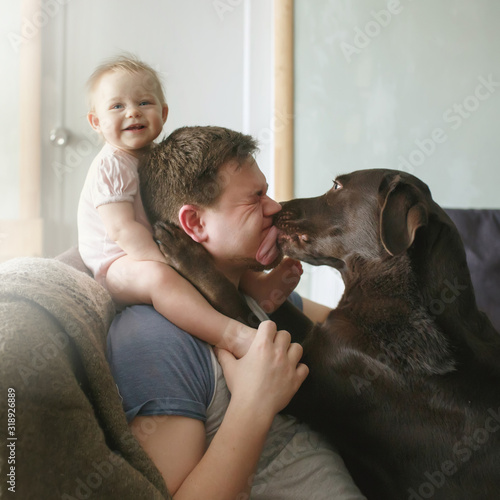 Obraz na płótnie Young handsome father with cute smiling little infant sitting on his shoulders and pet labrador retriever w salonie