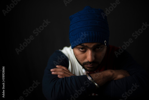 Fashion portrait of an young Indian Bengali brunette man in casual tee shirt and head band in black copy space background. Indian lifestyle and fashion photography.