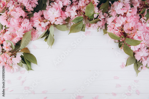 Sprigs of the sakura tree with flowers and petals on a wooden white background. Place for text. The concept of spring came. Top view. Flat lay