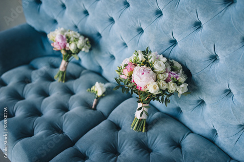 Photography Two multi-colored wedding bouquets with peonies and roses lies on the background of a blue sofa