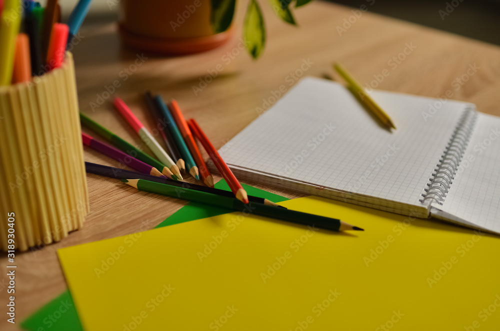 Notebook and color pencils on a desk. A cozy corner in the house. Notebook and color pencils on a desk. A cozy corner in the house.