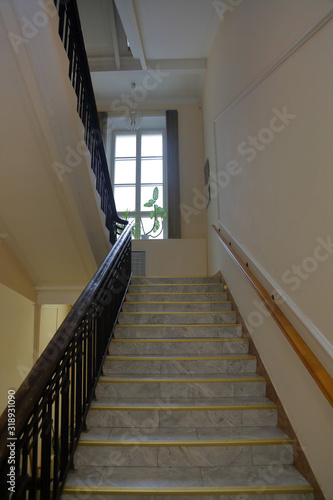 Old stone staircase with a handrail in a building without an elevator © ironstuffy