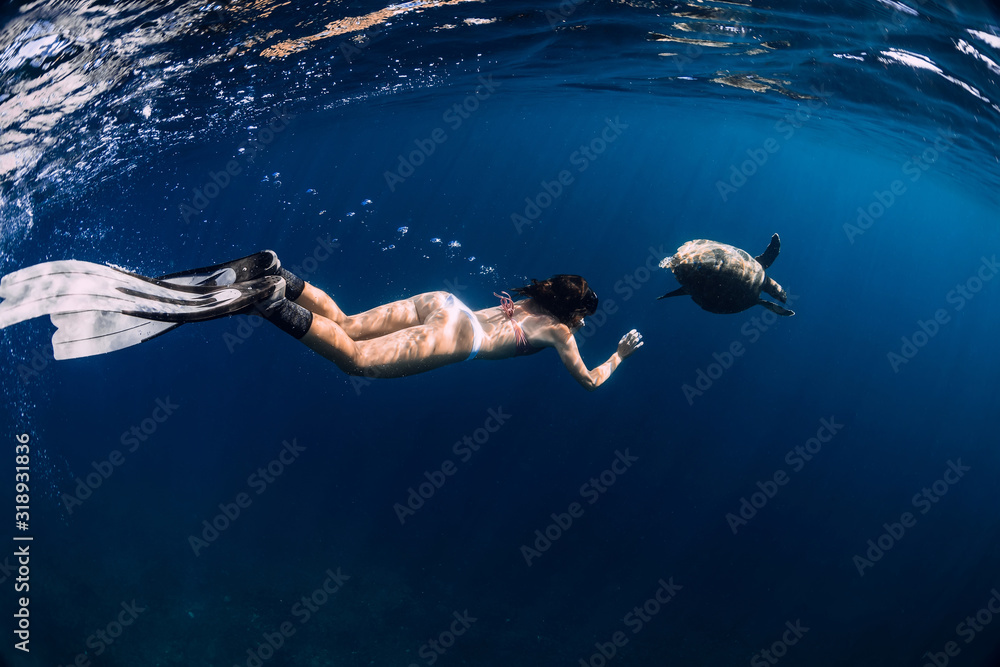 Snorkeling with sea turtle. Woman with fins swimming underwater with turtle.