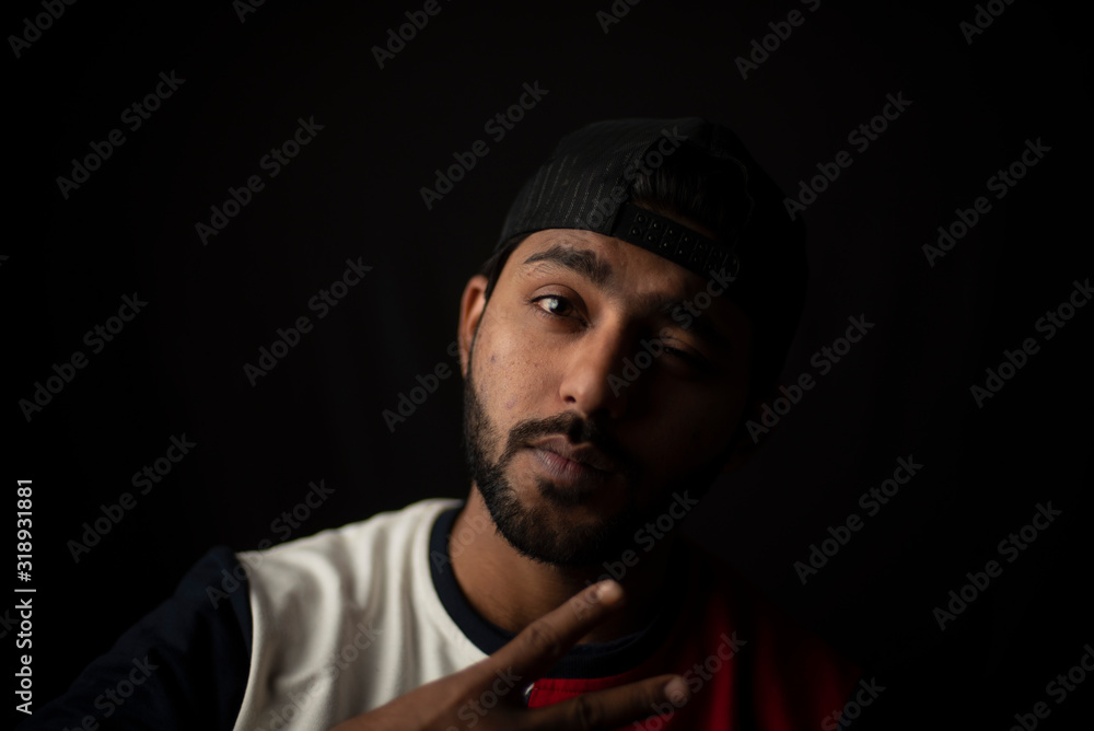 Fashion portrait of young and handsome Indian Bengali brunette man with casual tee shirt showing facial expression in black copy space background. Indian lifestyle and fashion photography Fashion portrait of young and handsome Indian Bengali brunette man with casual tee shirt showing facial expression in black copy space background. Indian lifestyle and fashion photography