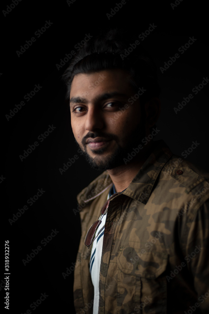 Fashion portrait of young and handsome Indian Bengali brunette man with casual camouflage shirt showing facial expression in black copy space background. Indian lifestyle and fashion photography Fashion portrait of young and handsome Indian Bengali brunette man with casual camouflage shirt showing facial expression in black copy space background. Indian lifestyle and fashion photography
