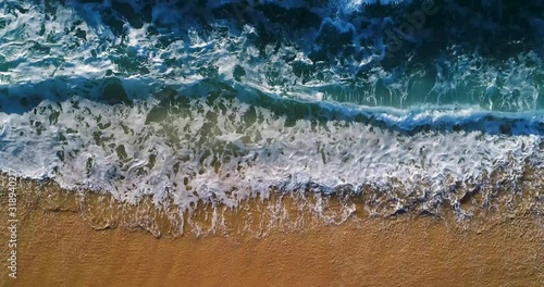 Aerial slow motion view of waves breaking at the beach in Comporta, Portugal