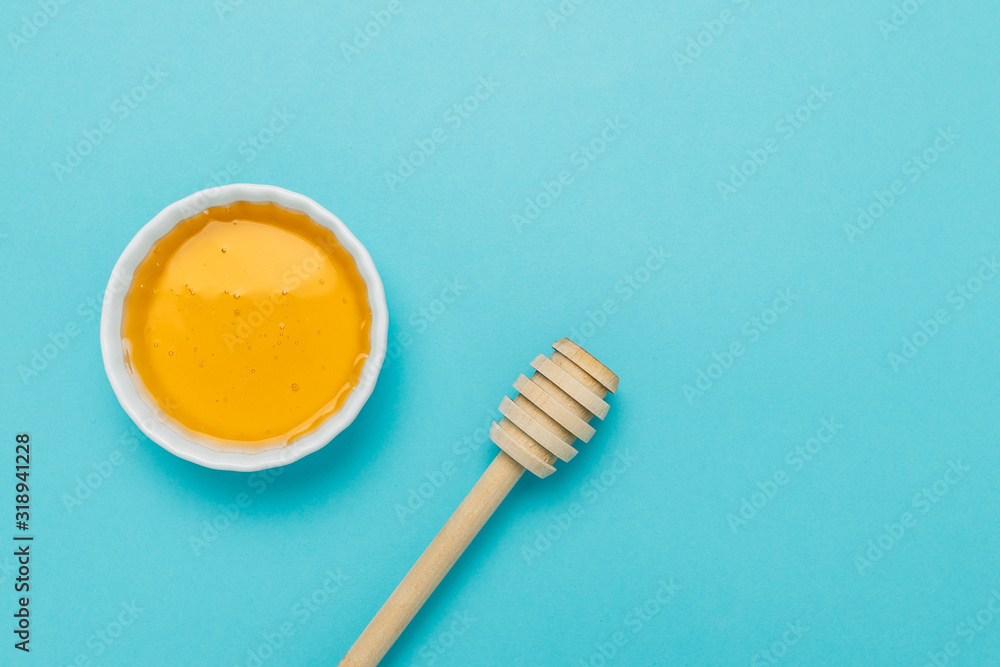 Honey bowl with honey deeper on blue background Honey bowl with honey deeper on blue background