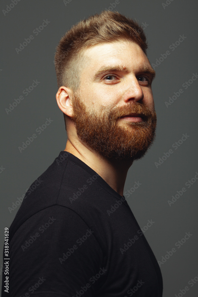 Fabulous at any age. Close up portrait of charismatic muscular 30-year-old man standing over dark gray background. Perfect haircut. Rocker, biker, hipster style. Studio shot