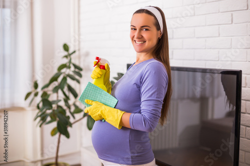 Beautiful pregnant woman enjoys cleaning her house.