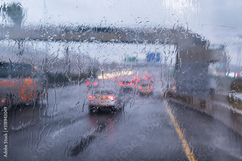 Traffic during rain on the highway, view through the windshield and focus on raindrops. Horizontal view.