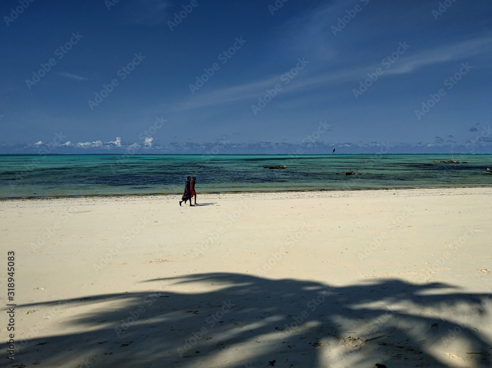 Zwei Massaii Krieger laufen den einsamen Strand am Meer auf Sansibar entlang Zwei Massaii Krieger laufen den einsamen Strand am Meer auf Sansibar entlang