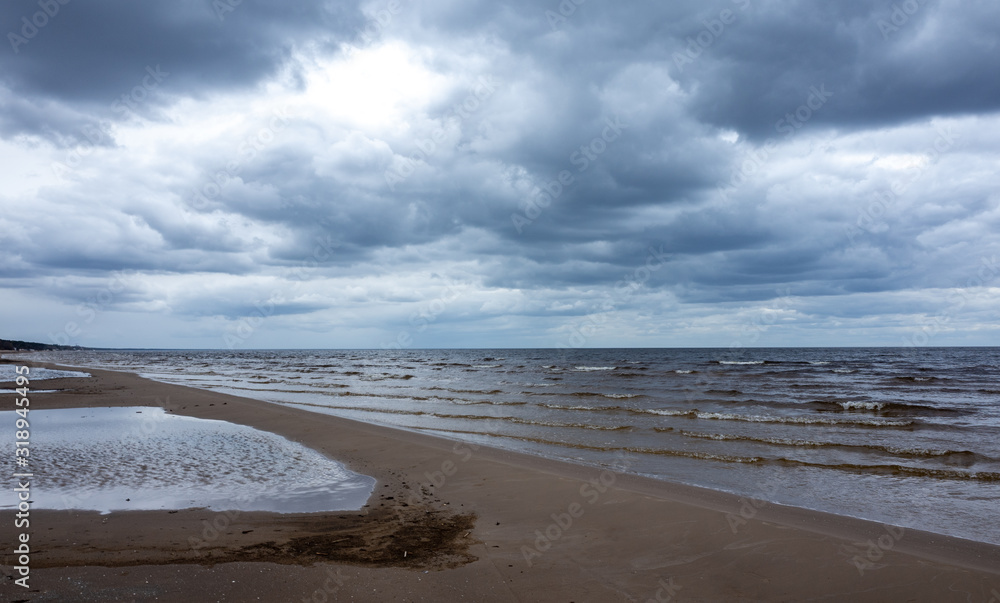 Reflection of clouds in a small lehman on the sandy shore of the Baltic Sea in Jurmala in cloudy weather.