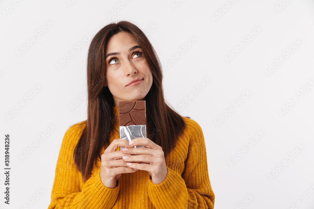 Image of beautiful adult woman hesitating while holding chocolate bar Image of beautiful adult woman hesitating while holding chocolate bar