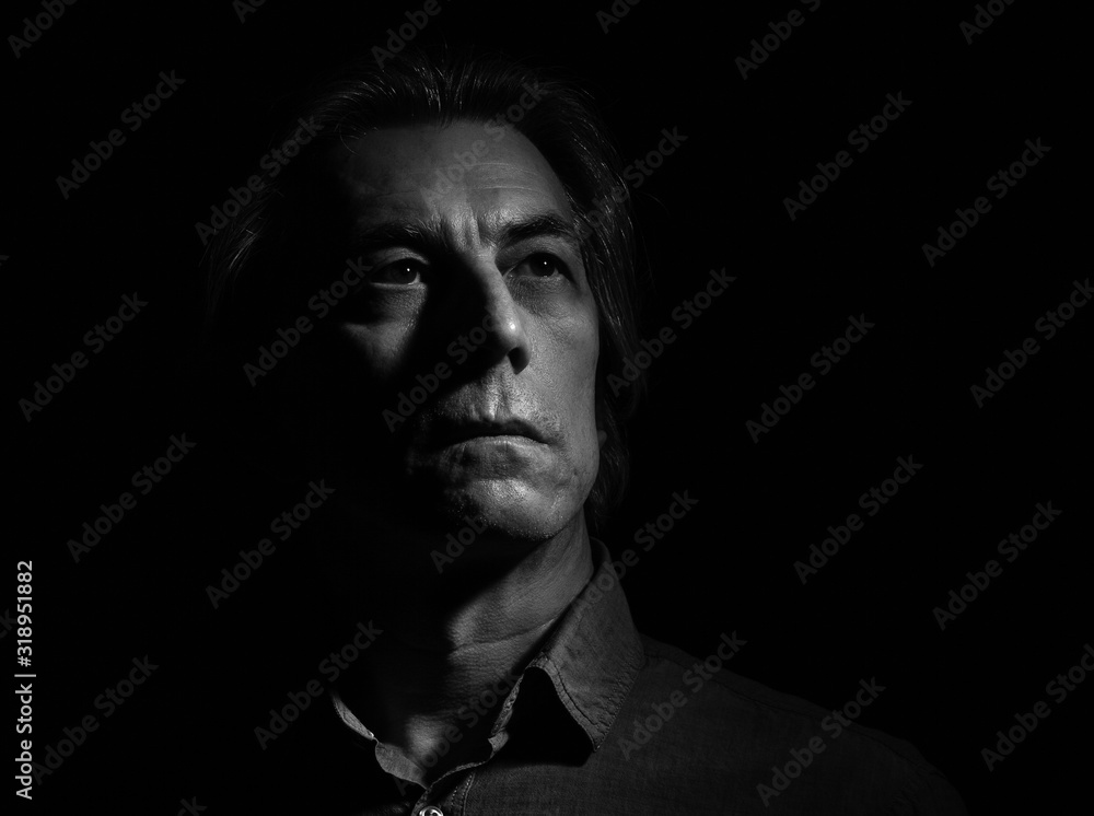 Obraz premium Portrait of a stern man on a black background with space for text.