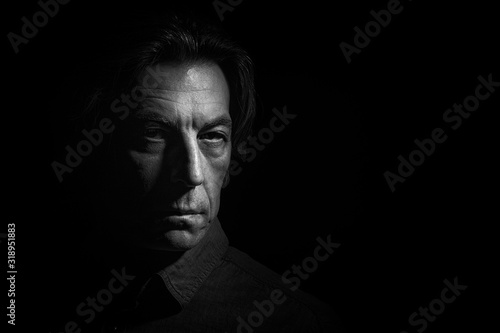 Portrait of a stern man on a black background with space for text.