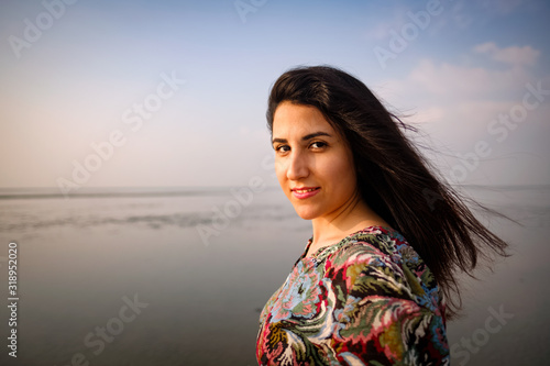 A portrait of smiling beautiful iranian persian girl outdoor on the beach looking at camera