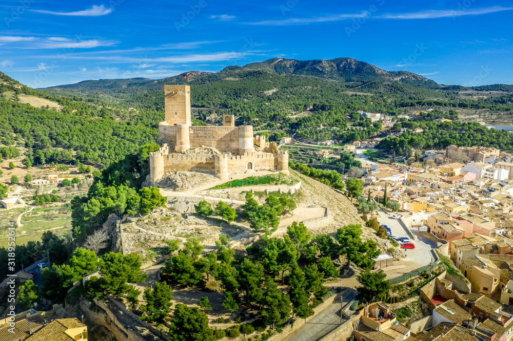 Aerial view of Biar castle in Valencia province Spain with donjon towering over the town and concentric walls reinforced with semi circular towers on a sunny day with blue sky