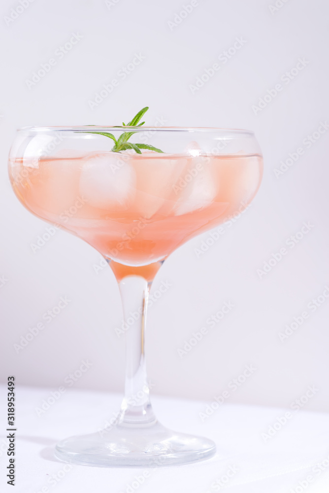 Pink cocktail with rosemary and ice on a white tablecloth on the table Pink cocktail with rosemary and ice on a white tablecloth on the table