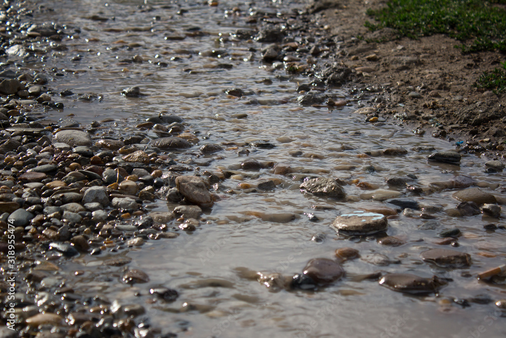A stream of rainwater running along a stony road A stream of rainwater running along a stony road